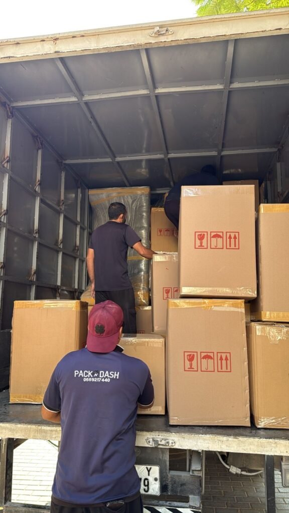 PacknDash movers stacking wrapped boxes and furniture into a moving truck in Dubai