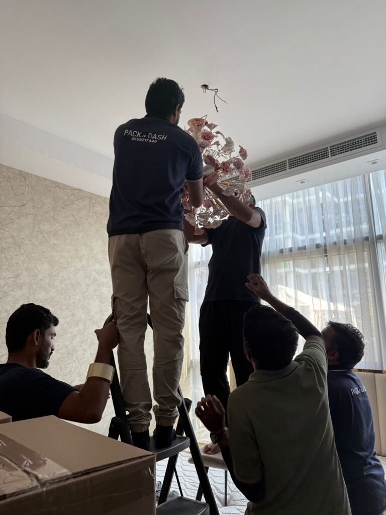 Movers in JLT (Jumeirah Lake Towers) Dubai 2 Four PacknDash movers carefully lowering a decorative chandelier from the ceiling before packing it