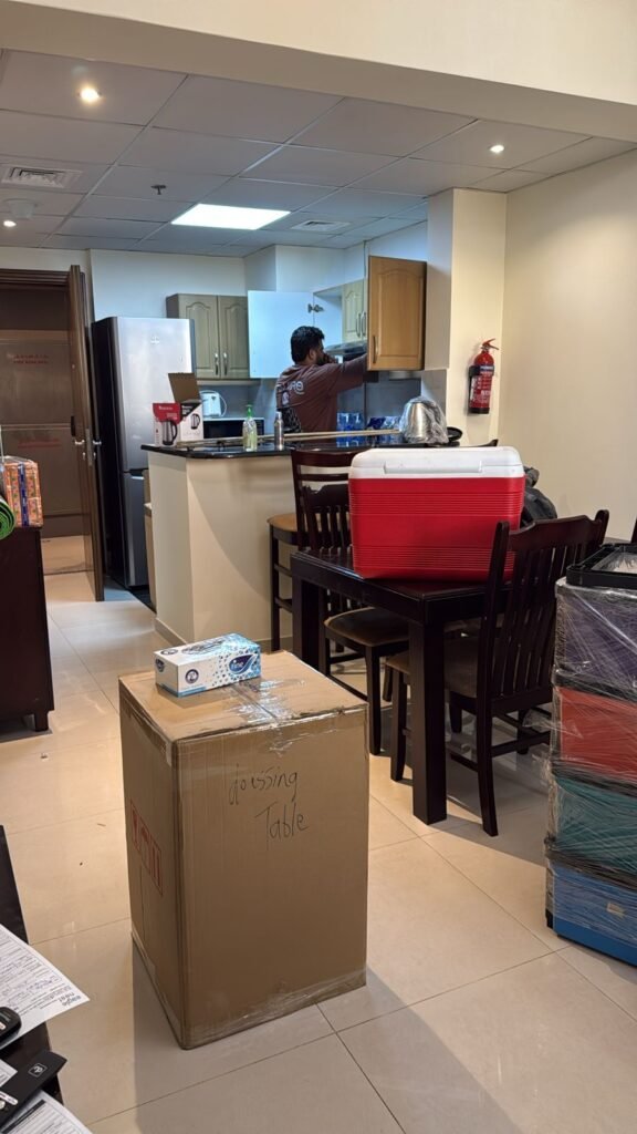 Labelled moving boxes and shrink-wrapped furniture stacked in a Dubai apartment mid-move
