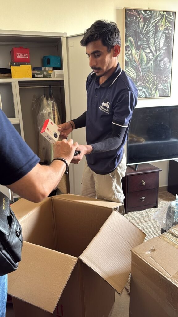 Movers and Packers Al Jaddaf Dubai 1 A PacknDash mover packing a small electronic item into a carton during an apartment move in Dubai