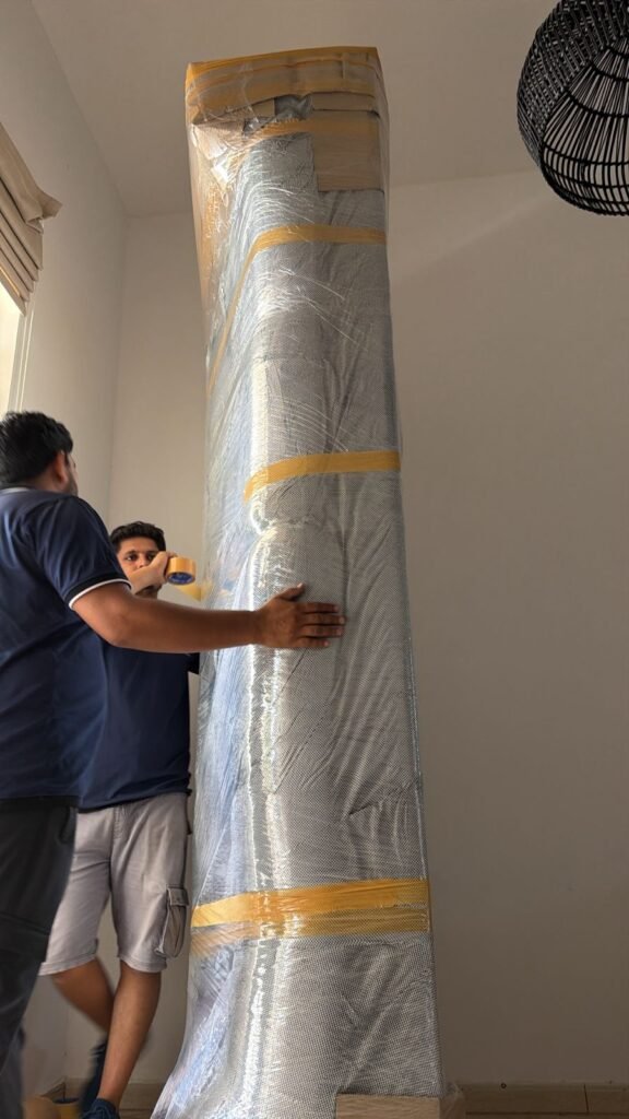 Movers and Packers Al Jaddaf Dubai 2 Two PacknDash movers wrapping and taping a mattress in protective covering before carrying it out